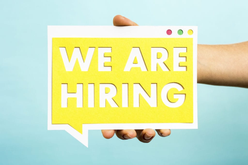 Hand holding we are hiring text with yellow paper on speech bubb
