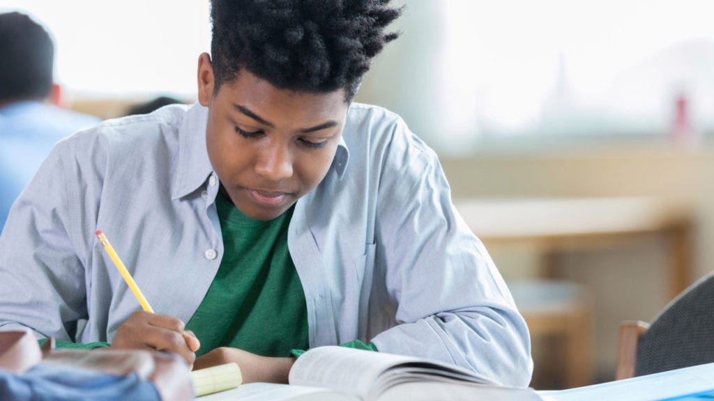 Teenage boy concentrates while studying in library